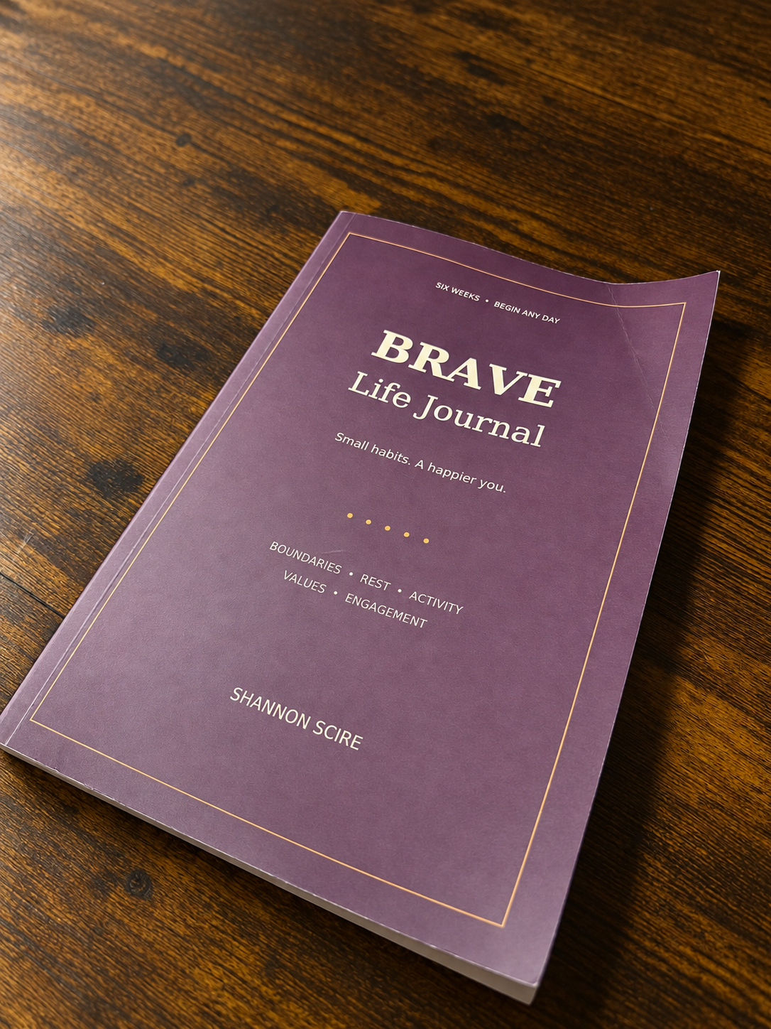The BRAVE Life Journal resting on a warm wooden desk